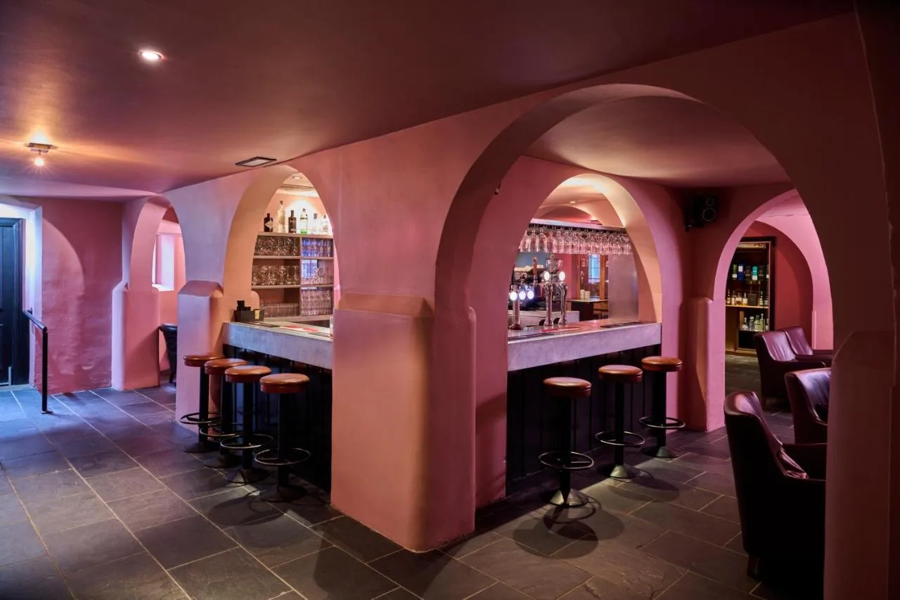 a bar in a restaurant with pink walls and stools at Hotel du Vin Birmingham in Birmingham