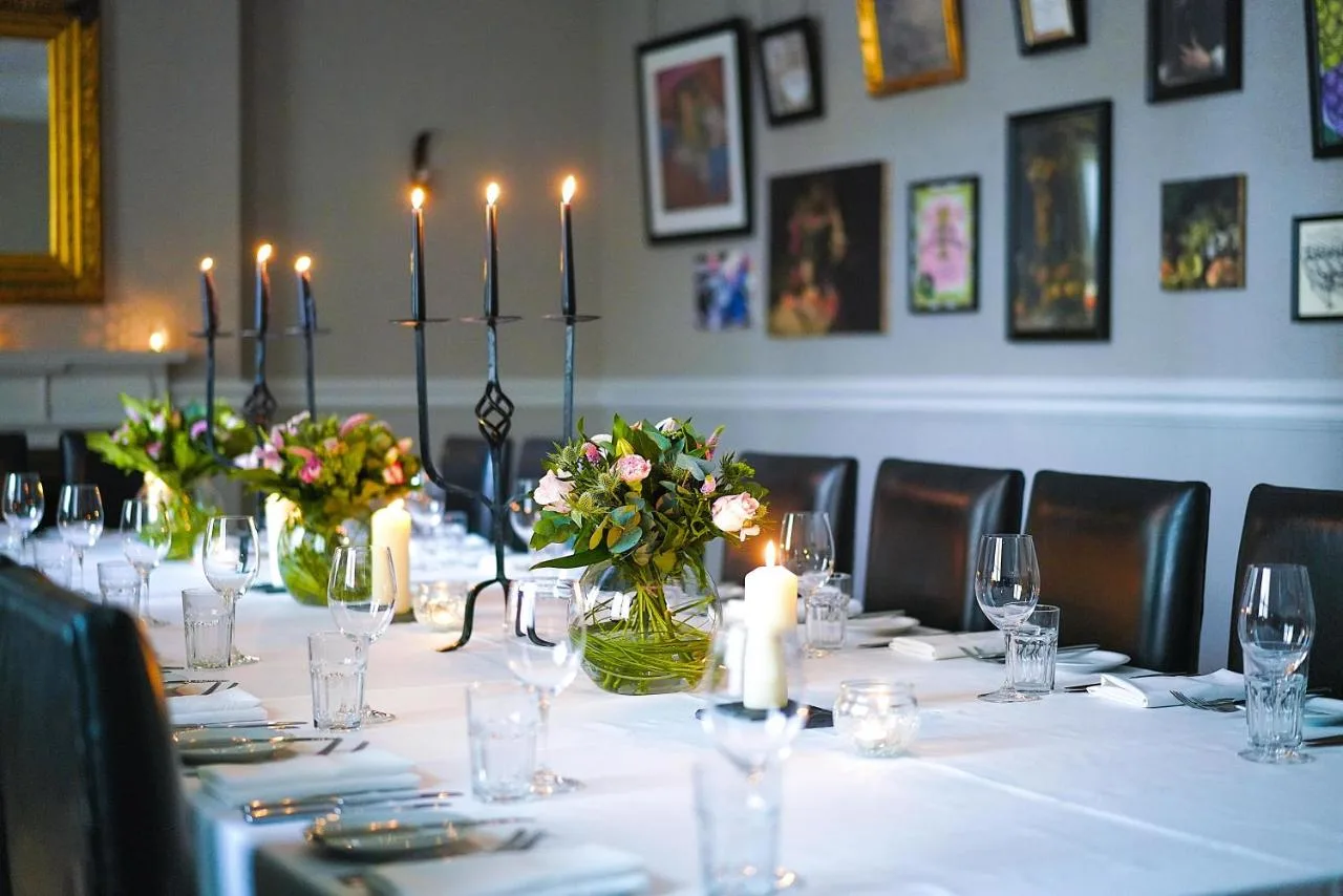a long table with candles and flowers in a room at Hotel du Vin Birmingham in Birmingham